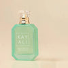 A mint green octagonal perfume bottle with a clear faceted cap and gold collar, labeled 'KAY ALI' on a warm beige background.