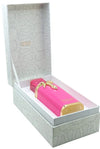 A pink cylindrical cosmetic bottle with gold trim and a gold bow, presented inside an open white patterned gift box. The bottle has a gold label reading 'Nikson' and a pink textured cap.