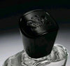 Black cylindrical container with a logo on top, placed on a clear base against a dark background