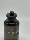 Black perfume bottle with 'Louis Vuitton' branding on a gray background