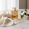 Chanel No. 5 perfume bottle on a marble surface with flowers and jewelry.