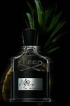 Creed Aventus perfume bottle on a dark background with a pineapple