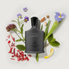 Creed Green Irish Tweed perfume bottle surrounded by flowers and leaves on a light background