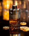 Luxury perfume bottle with gold coins on a reflective surface