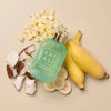 Perfume bottle labeled 'KAY ALI' surrounded by bananas, coconuts, and flowers on a beige background