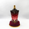 Perfume bottle shaped like a torso on a red stand with gold accents against a white background