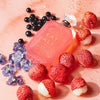Pink bottle of KAY ALI perfume surrounded by strawberries and berries on a pink background