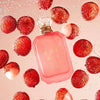 Pink perfume bottle with 'KAY ALI' branding surrounded by strawberries on a pink background