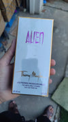 Thierry Mugler Alien perfume box held by a hand on a blurred background