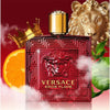 Versace Eros Flame perfume bottle with a gold lion, orange slice, and leaves on a red background